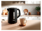Une bouilloire noire SilverCrest sur une table en bois à côté d'une tasse de thé.