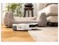 Aspirateur robot sur un tapis dans un salon avec pouf et canapé.