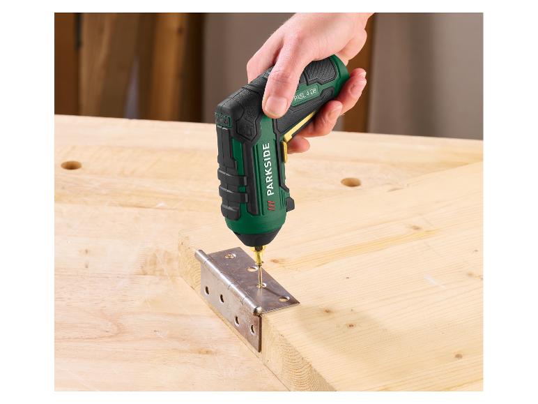 Une main utilise une visseuse sans fil pour fixer une charnière sur une planche en bois.
