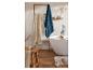 Salle de bain avec une baignoire, des serviettes, un tabouret en bois et des pantoufles.
