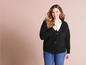 Une femme porte un pull noir et un jean bleu.