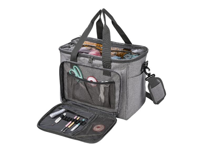 Un sac gris avec du fil, des aiguilles à crocheter et d'autres accessoires de couture