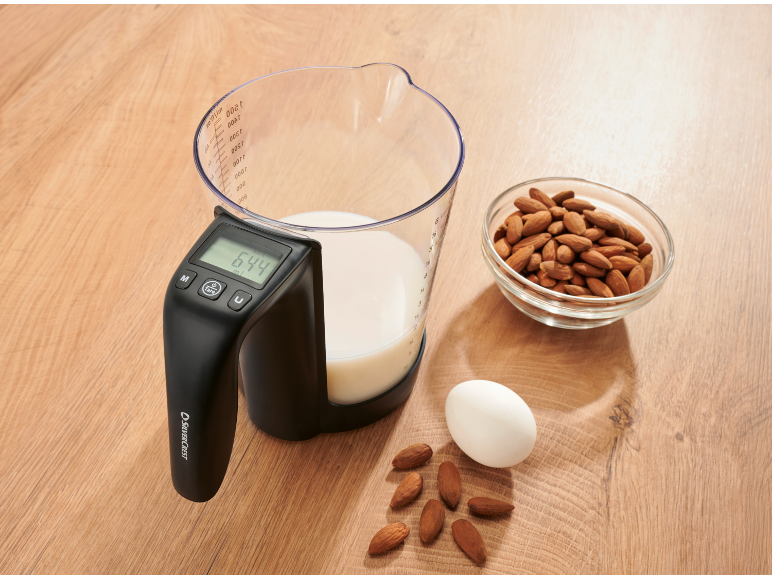Pichet doseur avec balance numérique affichant 644 ml, à côté d'amandes et d'un œuf.