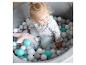 Une petite fille joue dans une piscine à balles avec des balles grises, blanches et bleues.