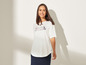 Une femme portant un t-shirt blanc avec un motif d'ancre et une jupe bleu marine.