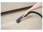 Une main utilisant un nettoyeur vapeur Silvercrest pour nettoyer un tapis.