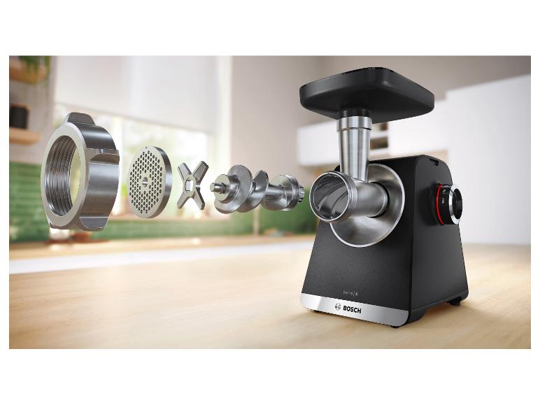 Vue éclatée d'un hachoir à viande avec ses composants disposés sur une surface en bois.