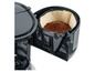 Une cafetière noire avec un porte-filtre rempli de café moulu.