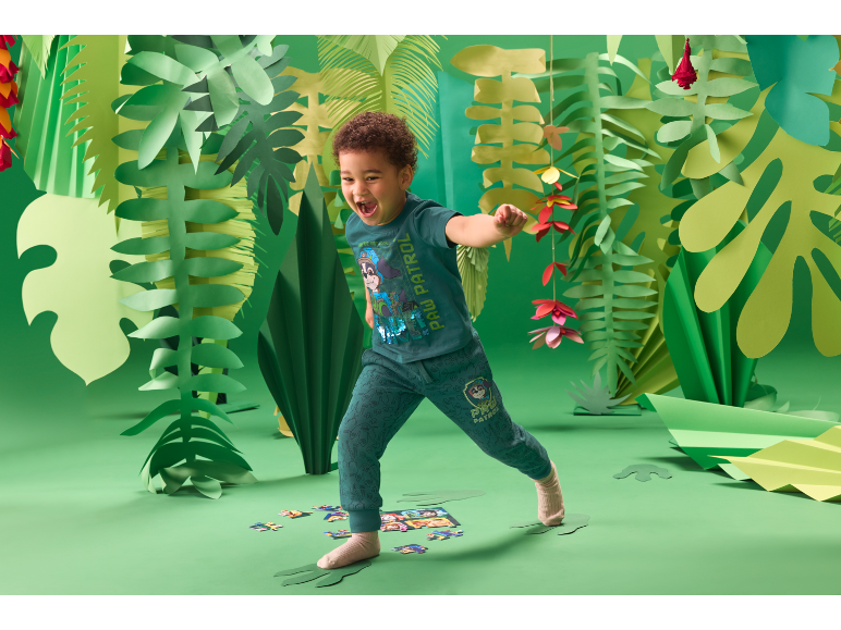 Enfant jouant dans un décor de jungle verte, vêtu d'une tenue Paw Patrol.