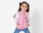 Une fille porte une veste bomber rose avec des papillons.