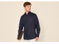 Homme portant une chemise à manches longues bleu marine, un pantalon blanc et un porte-documents marron.