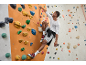 Homme escaladant un mur d'escalade avec un t-shirt à manches longues et un short de sport.