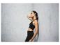 Une femme en soutien-gorge de sport et leggings noirs, avec une balle de massage sur le dos.