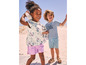 Deux enfants sur la plage, l'un avec un t-shirt imprimé d'une sirène et l'autre avec un t-shirt rayé qui dit 'Hello Summer'.