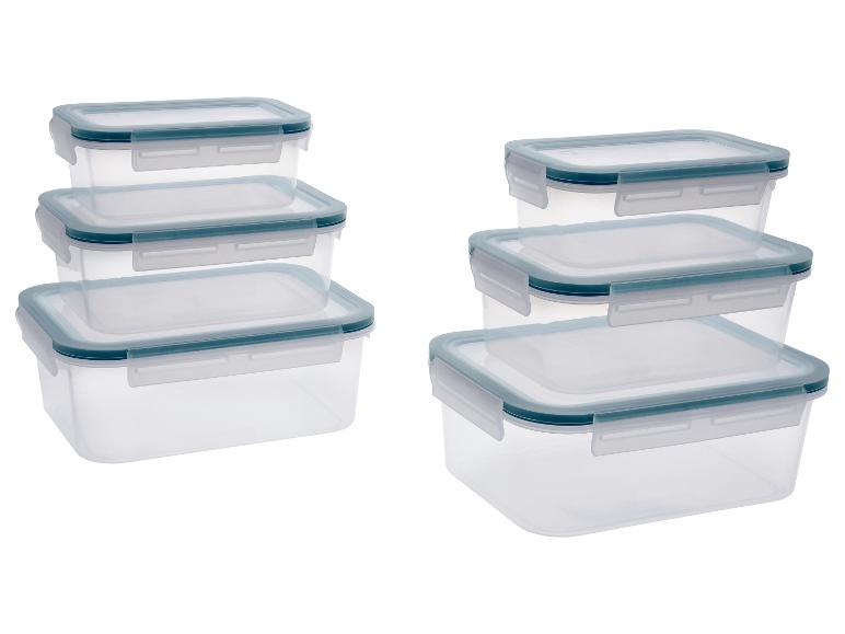 Récipients alimentaires transparents avec couvercles bleus, empilés en deux tas.