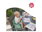 Un enfant assis sur une chaise avec un rehausseur de siège vert, boit dans une tasse bleue.