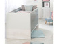 Un lit bébé avec des détails en bois et un tapis bleu clair.