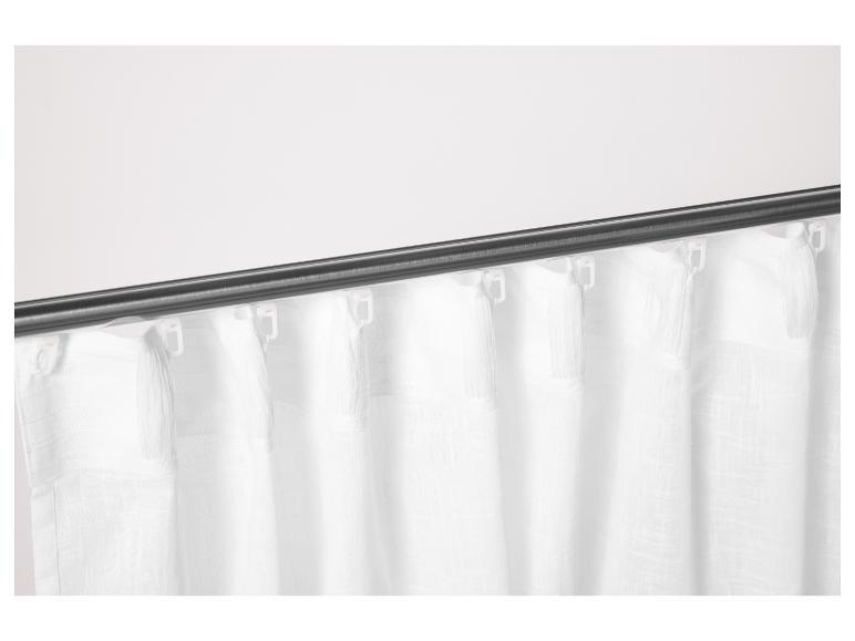 Des rideaux blancs à franges accrochés à une tringle sombre.