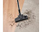 Aspirateur sur parquet et tapis avec de la saleté.