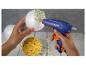 Pistolet à colle fixant des fleurs blanches sur une boule de polystyrène, une autre boule décorée de fleurs jaunes.