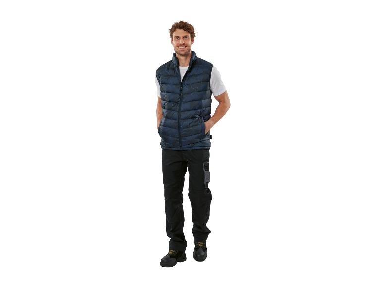 Homme portant un gilet matelassé bleu foncé, un t-shirt blanc et un pantalon de travail noir.