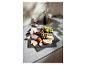 Plateau de fromages, charcuterie et fruits sur une surface grise.