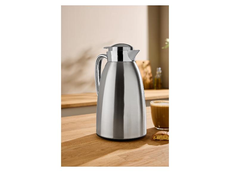 Verseuse isotherme en acier inoxydable sur un comptoir en bois avec café et biscuit.