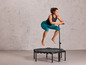 Une femme saute sur un trampoline avec une poignée.