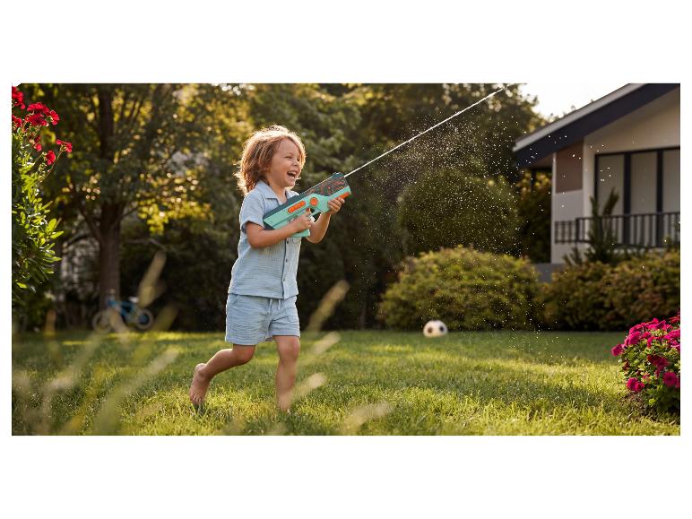 Enfant heureux jouant avec un pistolet à eau dans le jardin.
