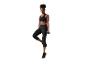 Femme en brassière de sport noire et legging, debout sur une jambe avec un haltère.