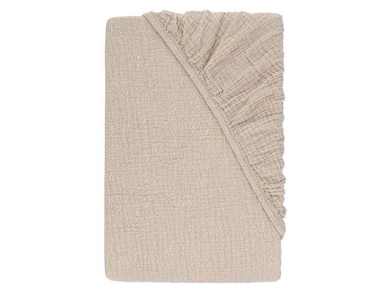 Drap-housse en mousseline de coton beige clair, plié.