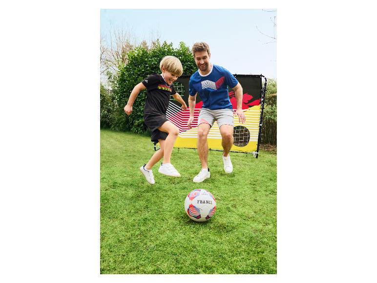 Père et fils jouant au football devant un but avec un drapeau allemand.