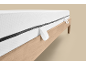 Matelas blanc avec fermeture éclair et poignées sur un cadre de lit en bois.