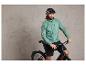 Un homme avec un casque et une veste fait du vélo sur un vélo noir.