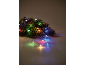 Branche de sapin de Noël avec des guirlandes LED colorées sur fond clair.