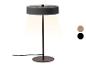 Lampe de table avec abat-jour et base gris foncé, émettant une lumière chaude, avec des échantillons de couleur.
