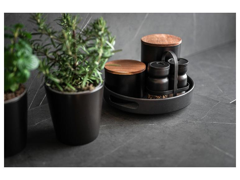 Ensemble d'épices noir avec détails en bois sur une table sombre.