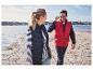 Un homme et une femme en gilets bleus et rouges marchent le long du rivage.