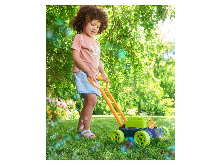 Un enfant joue avec une tondeuse à bulles dans le jardin.