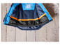 Une veste d'hiver bleue avec des détails orange et une étiquette de nom.
