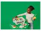 Une petite fille joue avec un barbecue jouet en bois, des brochettes et des aliments.