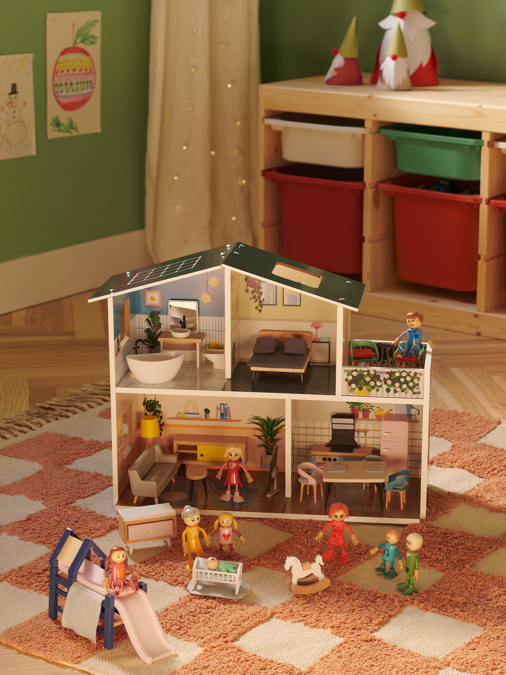 Maison de poupée en bois avec figurines et meubles, entourée d'un tapis et de jouets.
