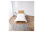 Un lit avec une tête de lit en bois et un tapis à motif géométrique.