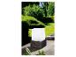 Une lampe extérieure blanche avec une base en rotin sur une terrasse en bois.