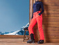 Femme vêtue d'un pantalon de ski rose vif et de chaussures de ski noires.