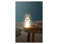 Une lampe de nuit en forme de lapin blanc sur une table en bois.
