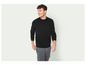 Un homme portant un pull noir et un pantalon gris.
