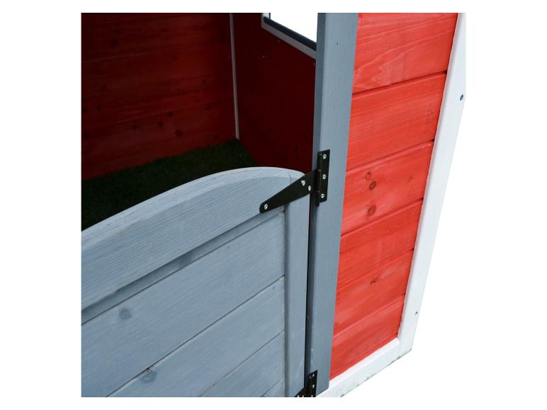 Intérieur d'une cabane de jeu en bois rouge avec une porte grise et un sol vert.