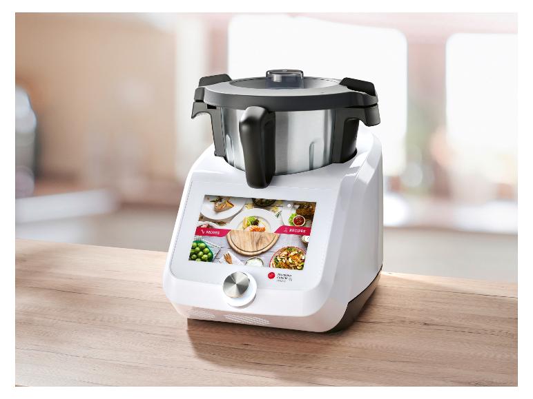 Robot de cuisine avec écran tactile affichant modes et recettes, sur une table en bois.