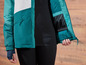 Une veste teal avec des panneaux blancs et noirs et un gant bleu foncé.